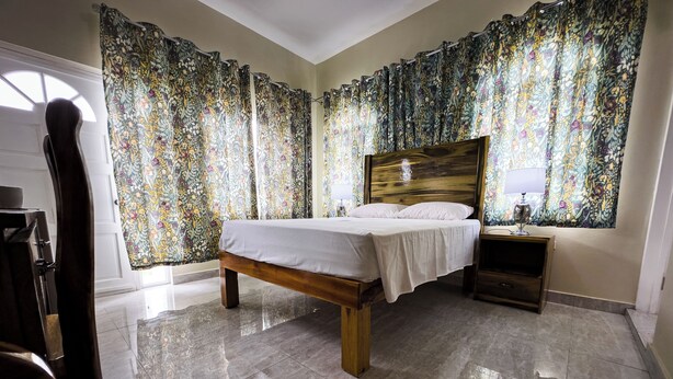 Une chambre à coucher avec un lit en bois, une table de chevet et des rideaux à motifs floraux.