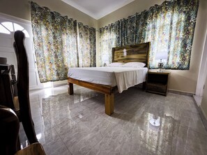Une chambre à coucher avec un lit en bois, une table de chevet et des rideaux à motifs floraux.
