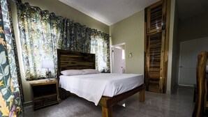 Une chambre à coucher avec un lit en bois, une table de chevet, un miroir et une porte.