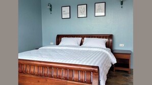 Un dormitorio con una cama de madera, una mesita de noche y tres cuadros en la pared.