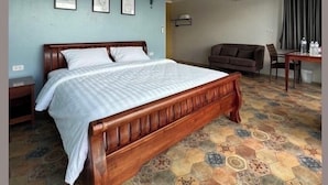 Una habitación de hotel con una cama de madera, un escritorio, un sofá marrón y un suelo estampado.