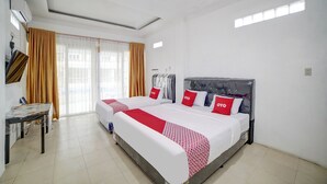 Una habitación de hotel con una cama grande, dos mesitas de noche, un escritorio y una ventana con cortinas.