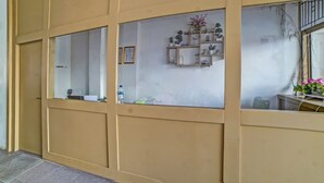 Una habitación con una puerta corredera, un estante con adornos y una mesita con un jarrón de flores.