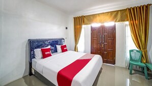 Una habitación de hotel con una cama, una puerta de madera y una silla verde.