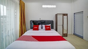 Una habitación de hotel con una cama, un armario, una ventana con cortinas y una lámpara en el techo.