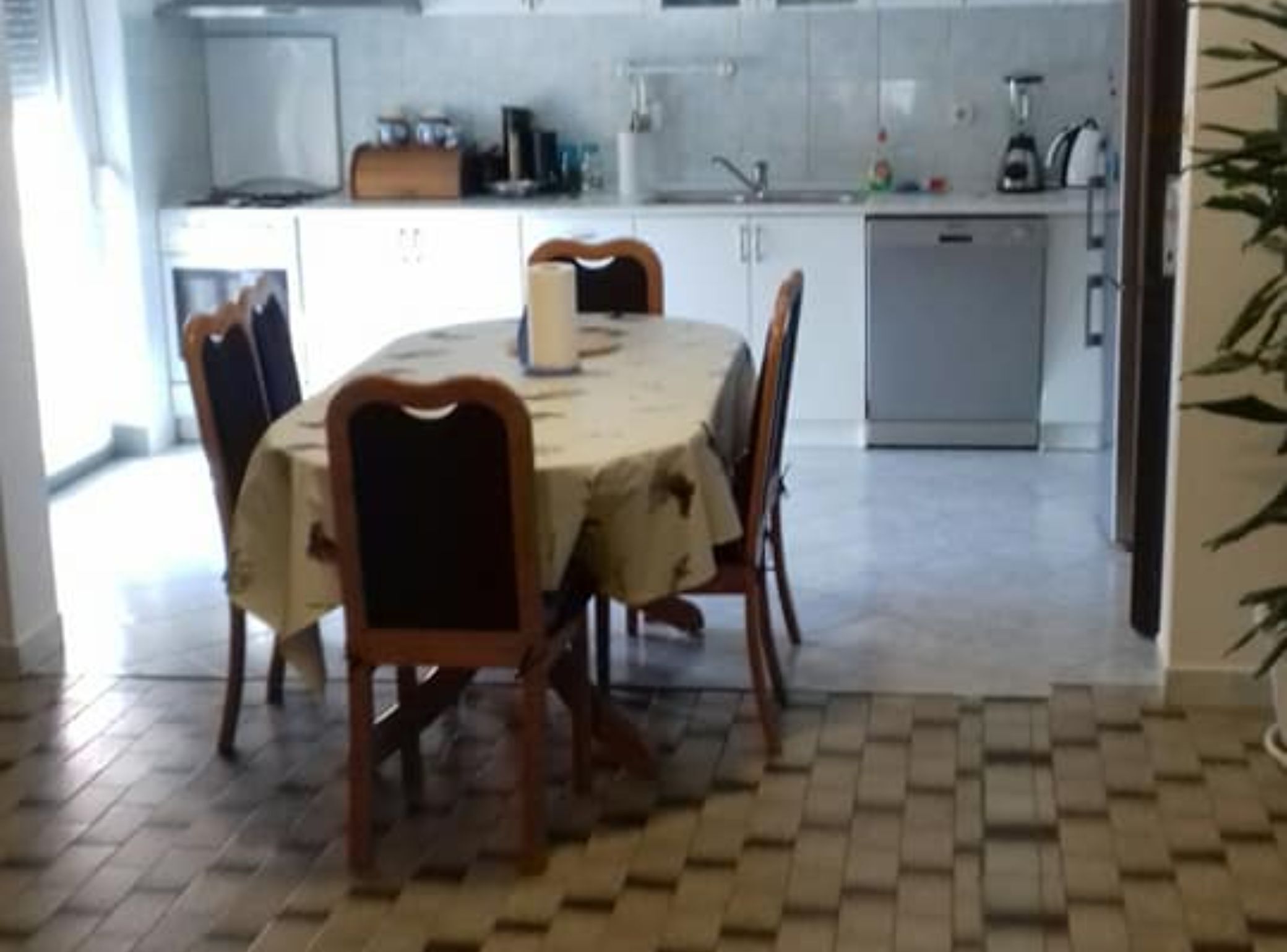 Un coin repas avec une table ronde, quatre chaises et un sol carrelé.