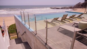 A poolside area with lounge chairs and a view of the ocean.