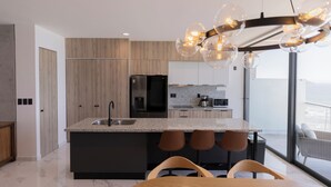 A modern kitchen with a central island, bar stools, and a dining area with a table and chairs.