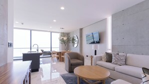 A modern living room with a sofa, coffee table, and a dining area with chairs and a table.