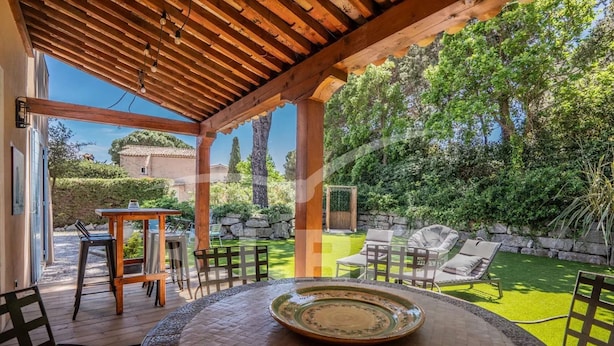 Une terrasse extérieure avec une table ronde, des chaises et une pergola.