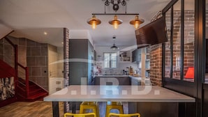 Une cuisine moderne avec un îlot central, des tabourets de bar jaunes et un mur en briques.