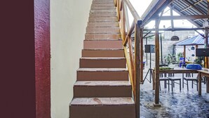 Una escalera conduce a un espacio exterior techado con una mesa y sillas.