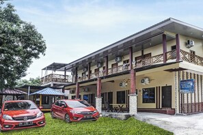 A two-story building with a covered outdoor seating area, air conditioning units, and a signboard.