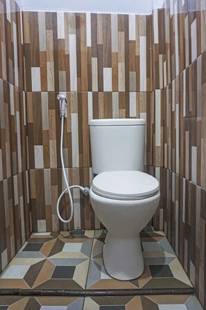 A bathroom with a toilet, a wall-mounted sink, and a tiled floor.