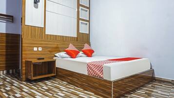 A modern bedroom with a wooden headboard, a bed with red and white patterned pillows, and a checkered floor.