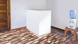 Una habitación con una puerta de madera, un pilar blanco y un dispensador de agua sobre un taburete.