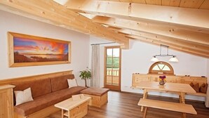 A cozy room with a wooden bench, a sofa, and a dining table. - Ferienwohnung Chiemsee (Bernau am Chiemsee)
