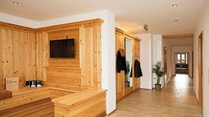 Moderni sisustus, jossa on puupanelointia, sisäänrakennettu oleskelualue, litteänäyttöinen televisio ja käytävä, joka johtaa toiseen huoneeseen.