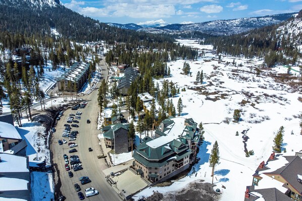 A large lodge with multiple buildings, a parking lot, and surrounding snow-covered landscape.