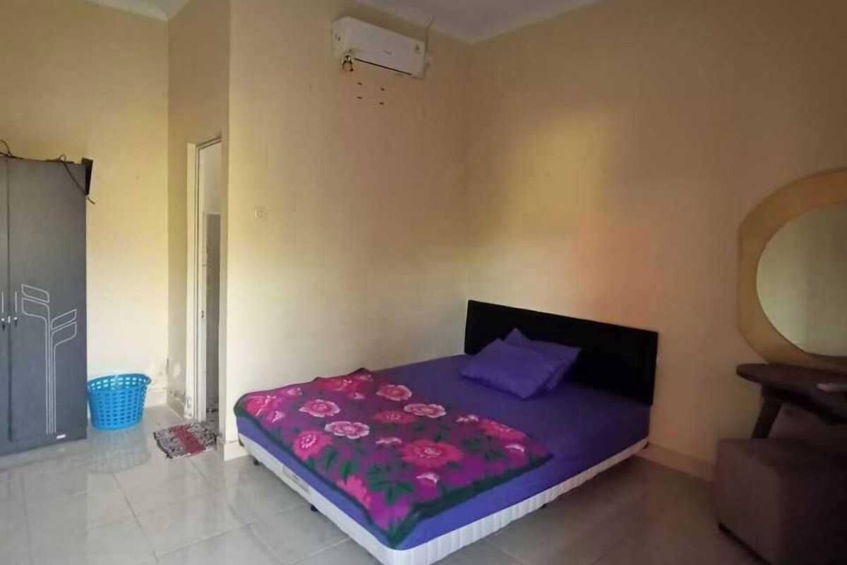 Un dormitorio con cama, armario, cesto azul y ventilador de techo.