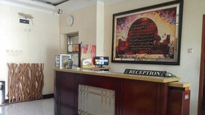 Una recepción con un cartel, un reloj y una obra de arte enmarcada en la pared.