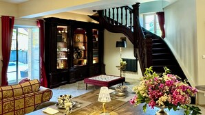 A spacious living room with a grand staircase, a wooden coffee table, and a bookshelf. - Dordogne, Luxury Cottage, Domme and Sarlat, Hamlet Château Giverzac, With Airco (Domme)