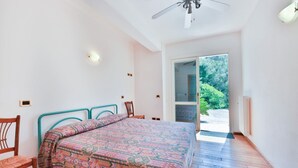A bedroom with a bed, a chair, a ceiling fan, and a view of the outdoors. - RELAIS NISPORTINO - BORGO AI PINI VILLA (Rio dell'Elba)