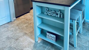 Eine Küche mit einem Edelstahl-Kühlschrank, einem eingebauten Backofen und einer Mikrowelle. Eine weiße Tür und ein Holzschrank befinden sich über der Spüle.
