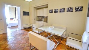 A modern kitchen with white cabinets and a built-in oven. There is a dining area with a white table and chairs. - Casa Arpeggio: An elegant and welcoming apartment located in the center of Maiori and a few meters from the sea. (Maiori)