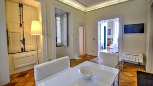 A modern hotel room with a white dining table, a white sofa, and a large window. - Casa Arpeggio: An elegant and welcoming apartment located in the center of Maiori and a few meters from the sea. (Maiori)