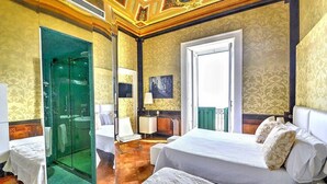 A hotel room with a bed, a glass-enclosed shower, a small table, and a chair. - Casa Arpeggio: An elegant and welcoming apartment located in the center of Maiori and a few meters from the sea. (Maiori)