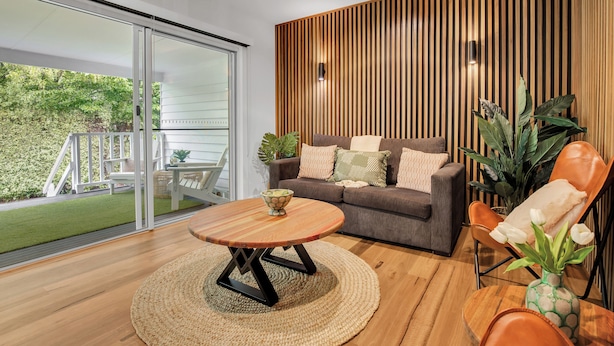 A modern living room with a sofa, coffee table, and a chair with a vase of flowers. - Bright on the River (Buffalo Apartment 1) (Bright)