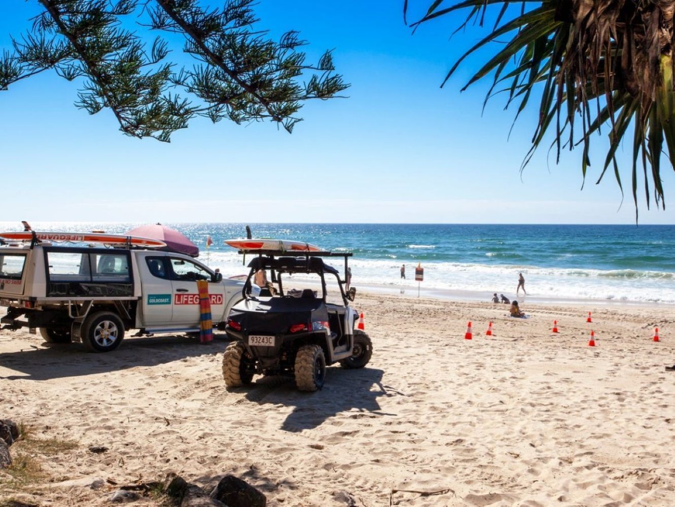 A beach with lifeguard vehicles and surfboards, indicating a beach safety presence.
