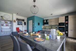 A modern kitchen with a teal accent wall, a dining area with a marble table, and a built-in oven.