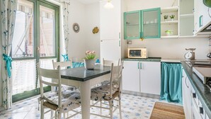 Una cucina con un tavolo da pranzo, sedie, un frigorifero e un forno a microonde.