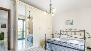 Una camera da letto con un letto, un armadio, uno specchio, un lampadario e un piccolo tavolo.