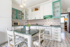 Cozinha com armários brancos, bancada verde e painel de azulejos.