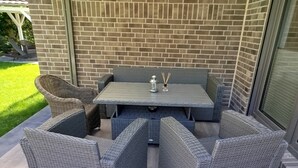 A patio with wicker furniture, a table, and a brick wall. - Holiday Home 'Ferienhaus Am Nationalpark' with Lake View, Wi-Fi and Air Conditioning (Klausdorf)