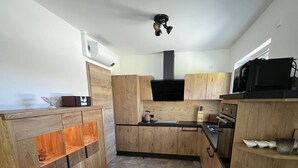 A kitchen with wooden cabinets, a black range hood, and a microwave. - Holiday Home 'Ferienhaus Am Nationalpark' with Lake View, Wi-Fi and Air Conditioning (Klausdorf)