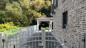 A gated entrance with a metal fence, a brick building, and a covered area with a tiled roof. - Holiday Home 'Ferienhaus Am Nationalpark' with Lake View, Wi-Fi and Air Conditioning (Klausdorf)