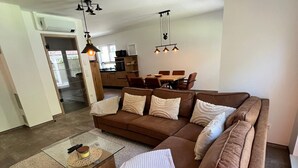 A modern living room with a sectional sofa, a glass coffee table, and pendant lighting. - Holiday Home 'Ferienhaus Am Nationalpark' with Lake View, Wi-Fi and Air Conditioning (Klausdorf)