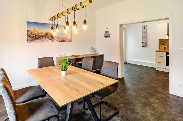 Un coin repas avec une table en bois, des chaises en cuir, une plante en pot et un luminaire fixé au mur.