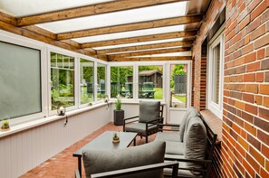 Une terrasse couverte avec un sol en briques, des poutres en bois au plafond et un mur en briques.