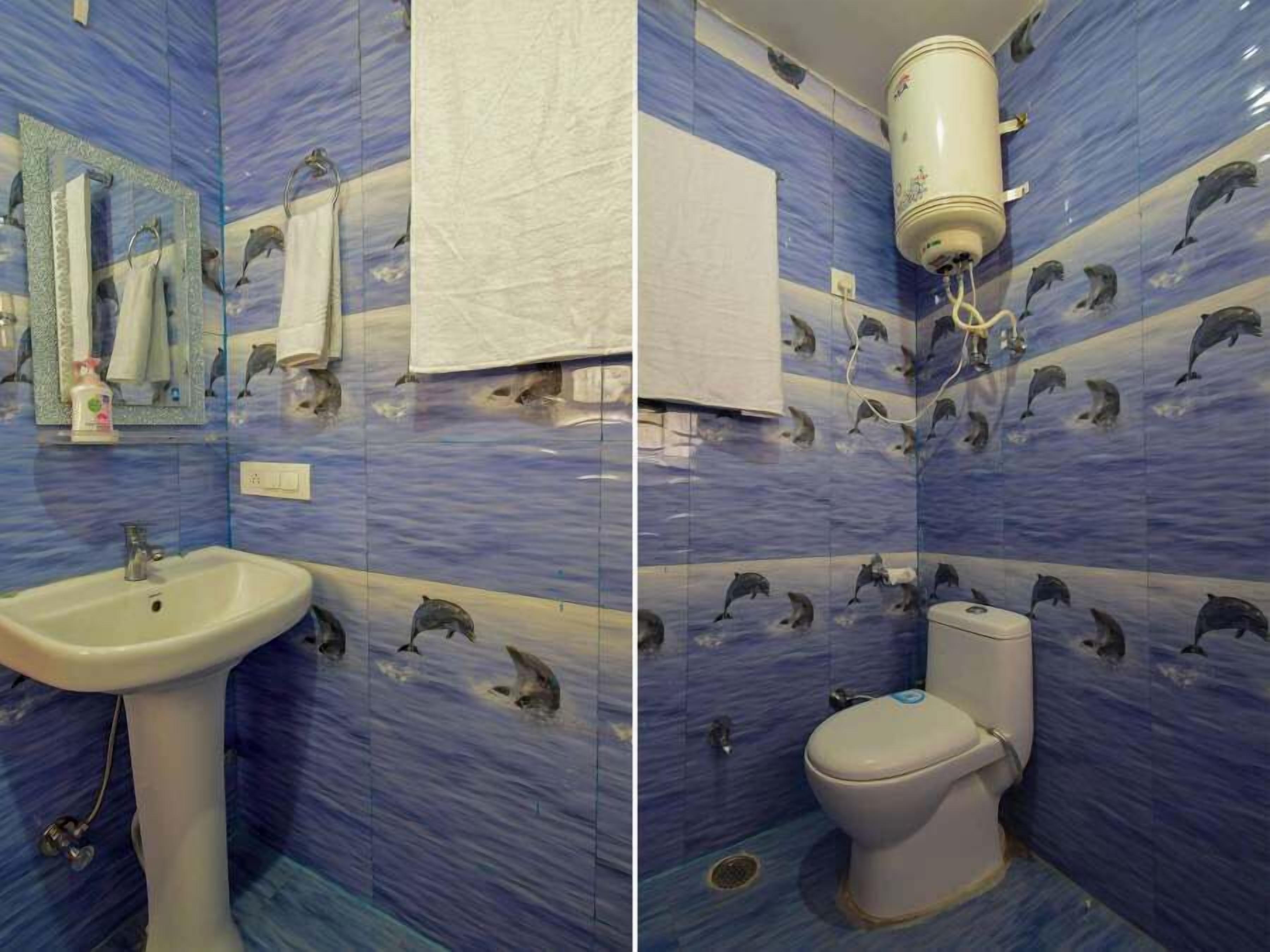 A bathroom with blue tiles featuring dolphin patterns, a white sink, and a toilet.
