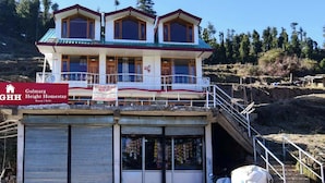 Edificio de hospedaje de dos pisos con balcón y entrada cubierta, con un letrero que indica que es el Hospedaje Gulmarg Height.