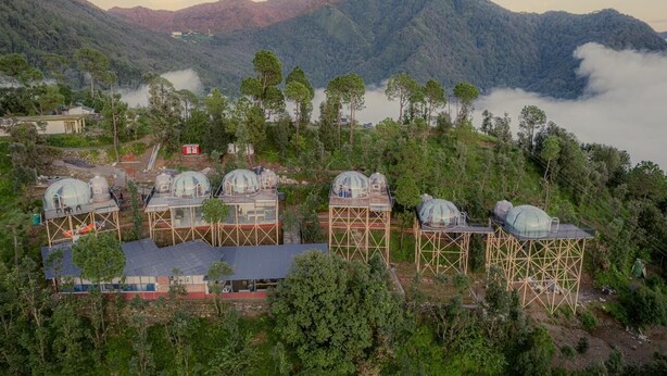 A series of dome-shaped structures on elevated wooden platforms, surrounded by lush greenery and mountains in the background. - Castle Glamp by Auroras Resorts (Kosiyakutoli)