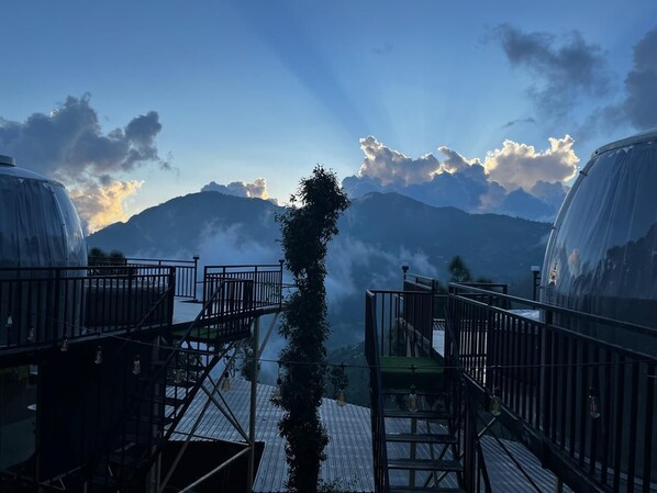 A view from a balcony with a mountain backdrop, featuring a glass-enclosed structure and a wooden deck. - Castle Glamp by Auroras Resorts (Kosiyakutoli)