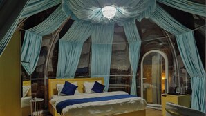 A bedroom with a bed, a chair, a small table, and curtains. - Castle Glamp by Auroras Resorts (Kosiyakutoli)