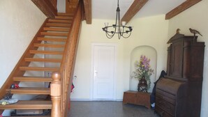 A wooden staircase, a chandelier, a white door, a wooden cabinet, and a vase with flowers. - Hoffarth Apartment with Private Terrace, Garden, and Wi-Fi (Gelting)