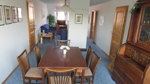 A dining room with a wooden table, six chairs, a vase of flowers, and a wooden cabinet. - Hoffarth Apartment with Private Terrace, Garden, and Wi-Fi (Gelting)